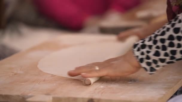 Woman hands with large gold ring roll dough on wooden board — Stock Video