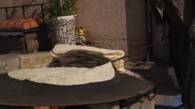 Eldivenli kadın, lavaşını kızartma yüzeyine yakın çekim için hazırlıyor.