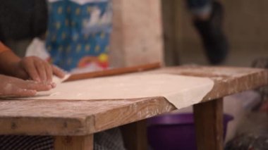 Turuncu kazaklı kadın özel uzun iğneli hamuru yuvarlıyor.