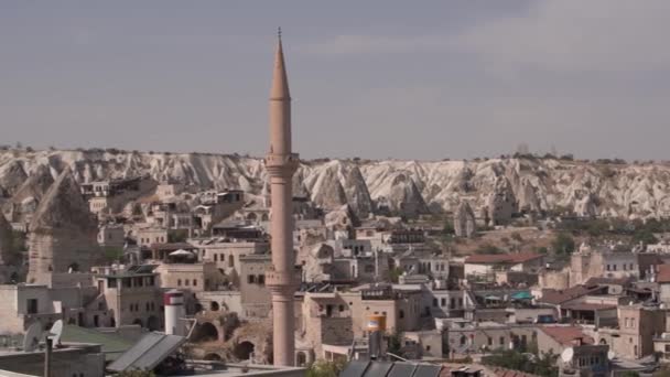 Высокий минарет мечети с острым шпилем по каменным зданиям — стоковое видео