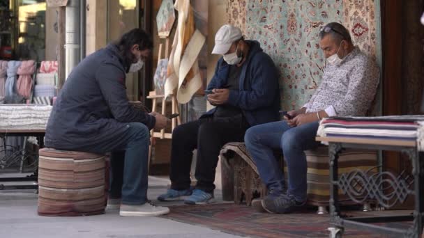 Local guys sit on designed chairs selling carpets in shops — Stock Video