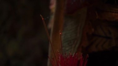 Yarı karanlık tapınakta yanan aromatik çubuklar.