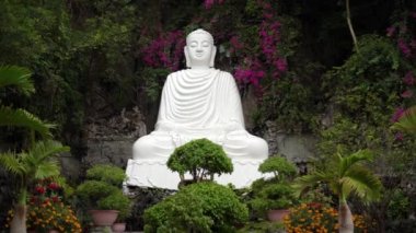 Bitkiler ve çiçekler arasında dingin Buda heykeli