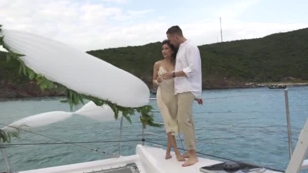 Szczęśliwa para z szampanem stoi na pokładzie jachtu na wietrze — Wideo stockowe