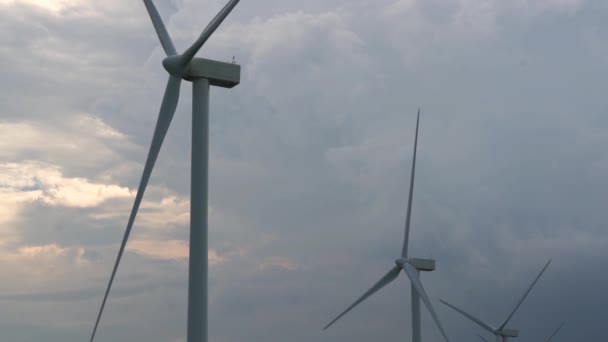 Moinhos de vento cinzentos altos com grandes lâminas rotativas no parque eólico — Vídeo de Stock
