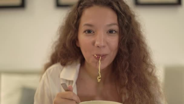 Cheerful mixed race lady with curly hair eats noodles — Stock Video