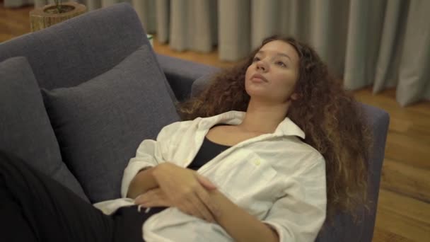 Wanita muda lelah melihat ke langit-langit berbaring di sofa abu-abu — Stok Video