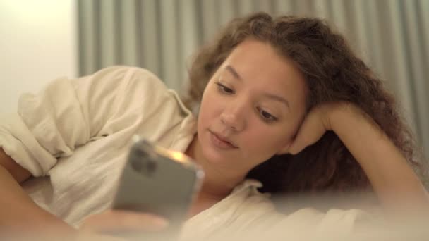 Entspannte Mischlingsdame mit langen lockigen Haaren liest Artikel — Stockvideo