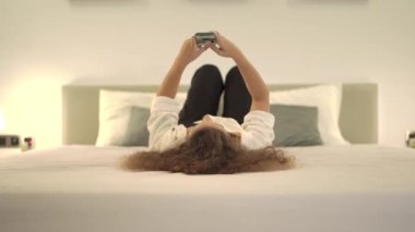 Beyaz tişörtlü kadın akıllı telefondan online oyun oynuyor.