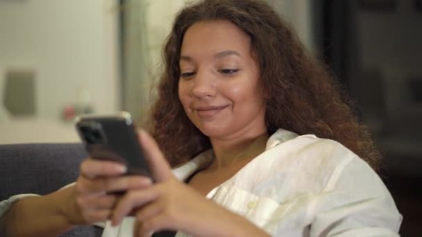 Mujer joven morena en camisa lee mensaje en smartphone — Vídeo de stock