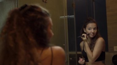 Karışık ırk modeli aynaya yansıyan makyaj uygular