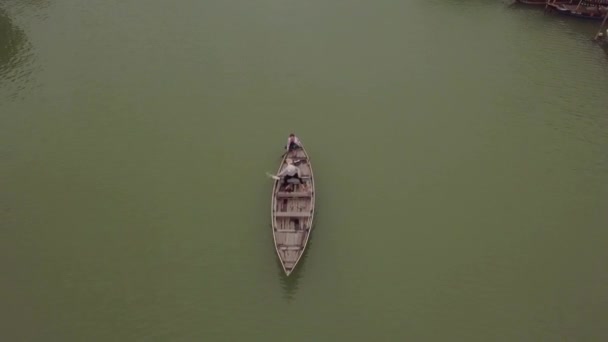 Hoi An river surface man rows boat and friend bails water — Stock Video