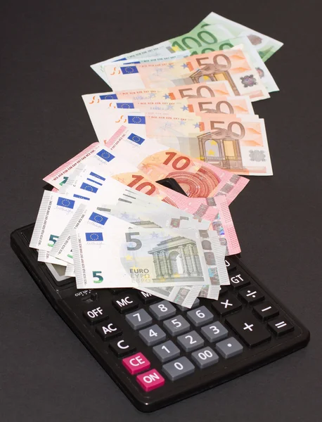 Bank notes of European money and calculating machine on black background — Stock Photo, Image