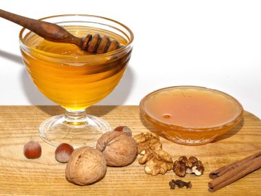 büyük ve küçük kase ballı, karanlık ve aydınlık tatlım kepçe ve metal kaşık ve fındık ve ceviz ahşap tablo