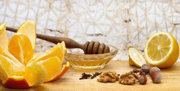 portakal, limon ve bal ve bal ayı fındık, ceviz ve karanfil ahşap masa üzerinde bir küçük kase