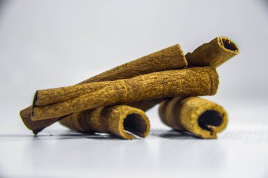 Kahverengi çiğ organik tarçın rulosu, baharatlar, dekorasyon grafik tasarımı, kapalı yemek stüdyosu çekimi, beyaz arka planda izole edilmiş, seçici odak, sığ alan derinliği, Kahire Mısır 'da çekilmiş