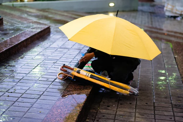 Migrant selling umbrellas in rain