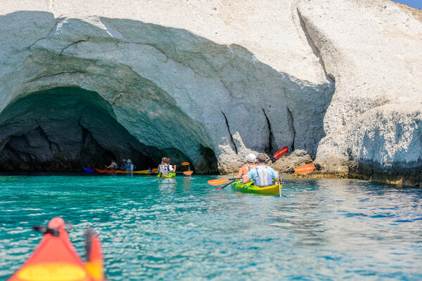 Люди на байдарках в пещерах, Мелос, Греция

