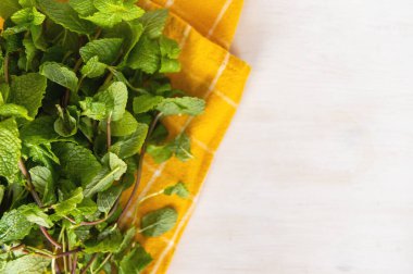 Organik taze nane. Beyaz ahşap arka planda sarı bir havlunun üzerinde nane yaprakları yıkadım. Düz yatıyordu.