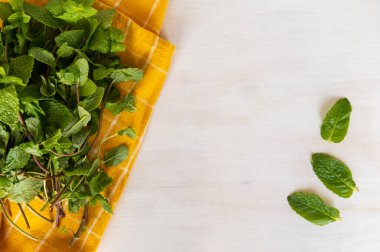 Organik taze nane. Beyaz ahşap arka planda sarı bir havlunun üzerinde nane yaprakları yıkadım. Düz yatıyordu.