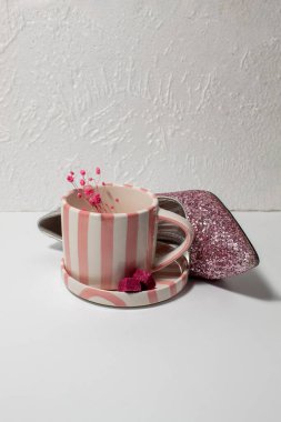 Yüksek topuklu pembe parıltılı topuklar çizgili kahve fincanı, şeker küpleri ve beyaz arka planda narin çiçeklerle eşleştirildi. Kadınsı moda ve yaşam tarzı konsepti.