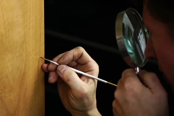 Restorers hands with magnifying glass and brush — Stock Photo, Image