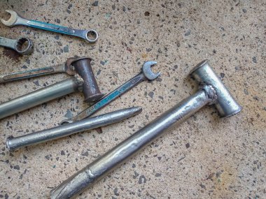 Eski atölye aletlerinin, kaynaklı çekiçlerin ve beton zemindeki anahtarların üst görüntüsü