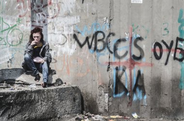 eski kirli düzensiz giysiler içindeki genç kız, bir rock ve enkaz üzerinde oturan ayakkabı bir sigara ve bir eşleşme tutan etrafında dağınık. Evsiz kız. Evsiz bir genç.