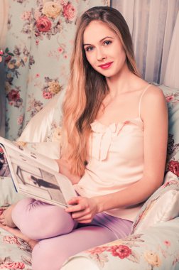 kucağında bir dergi tutarak ve dört gözle gülümseyen güzel genç sarışın