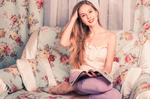 Belle jeune blonde tenant un magazine sur ses genoux et souriant impatient — Photo