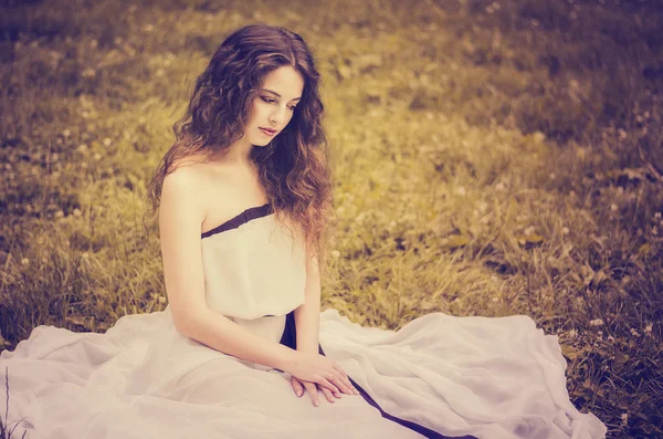 Menina bonita com cabelo luxuoso em um vestido branco longo com ba — Fotografia de Stock