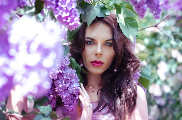 Portret atrakcyjne, romantyczny brunetka w rózowej sukni z kwiatami bzu bush — Zdjęcie stockowe