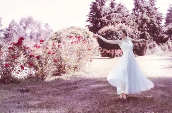 可爱、 有吸引力、 温柔、 浪漫、 性感的女孩在一个浪漫的发型，穿着一件白色的连衣裙。她在苍翠繁茂的花园里跳舞。新娘。芭蕾舞蹈家. — 图库照片