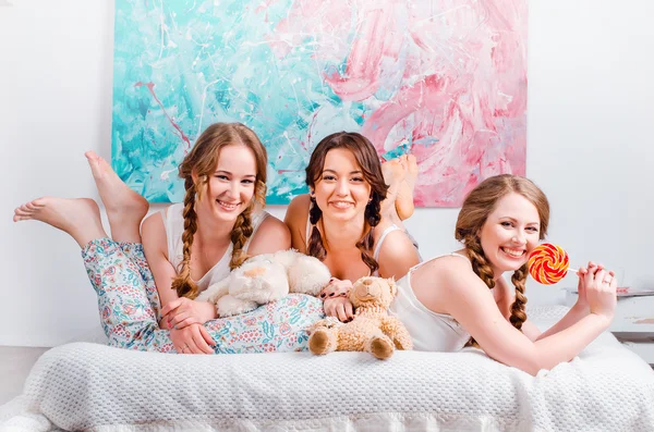 Три милые молодые девушки седат на кровати в комнате, являются holdin — стоковое фото