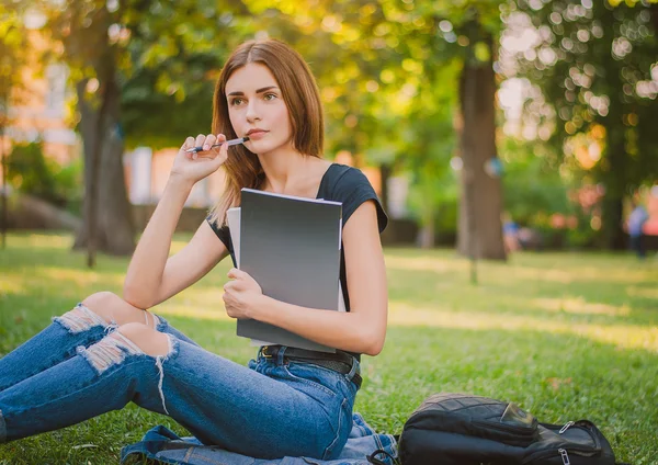 Enfocado chica estudiante sentado en la hierba con libros en su ha — Foto de Stock