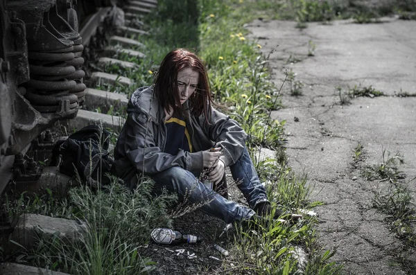 Молода жінка в старому брудному, розпусному одязі сидить на землі — стокове фото