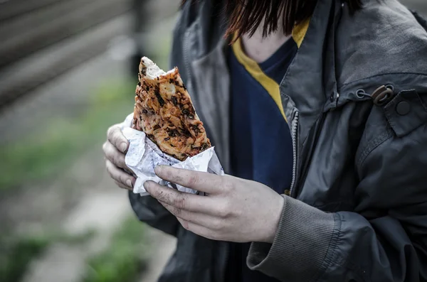 dirty old man in dirty clothes, holding a pizza slice