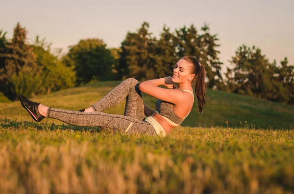 Fitness atrakcyjna młoda kobieta siedzi na trawie w parku czy — Zdjęcie stockowe