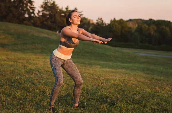 Aantrekkelijke fitness vrouw oefenen in het park op het gras. Sh — Stockfoto
