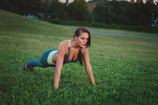 Jovem mulher atraente treinando no parque. Tábua de exercício. Apto. — Fotografia de Stock