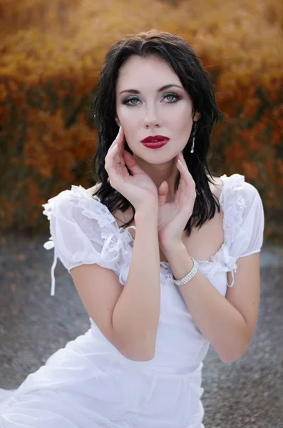 Hermosa chica en un vestido blanco en el jardín de otoño — Foto de Stock