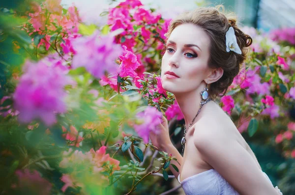 Retrato de una hermosa chica en ryzhoy delicado vestido azul, bellamente decorado piedra lunar en el exuberante jardín de azaleas — Foto de Stock