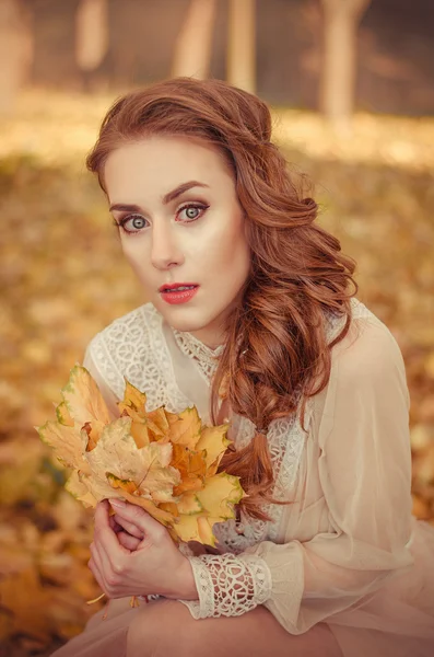 Portrait of a beautiful young girl with and braided hair and a bouquet of autumn leaves in the hands, a gentle long dress — Φωτογραφία Αρχείου