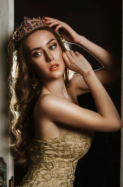 Portrait of a beautiful brown-haired woman in a gold dress and crown — Stok fotoğraf