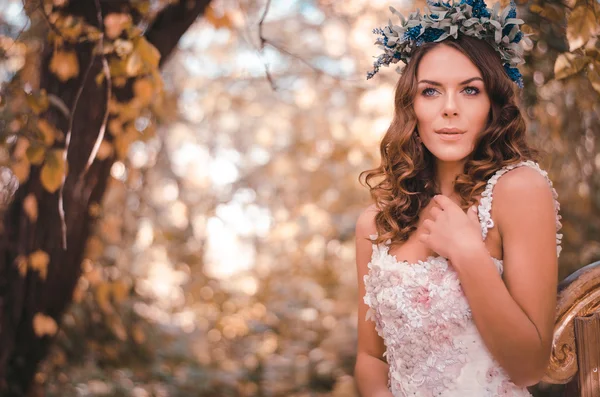 Retrato de una hermosa mujer de cabello castaño en una corona de flores sentada en el bosque de otoño cerca del arpa —  Fotos de Stock