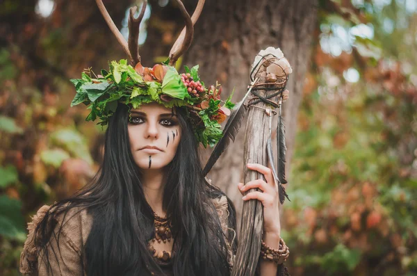 Porträt einer schönen Brünetten in Form einer Schamanin mit Blumenkranz auf dem Kopf und Hörnern — Stockfoto