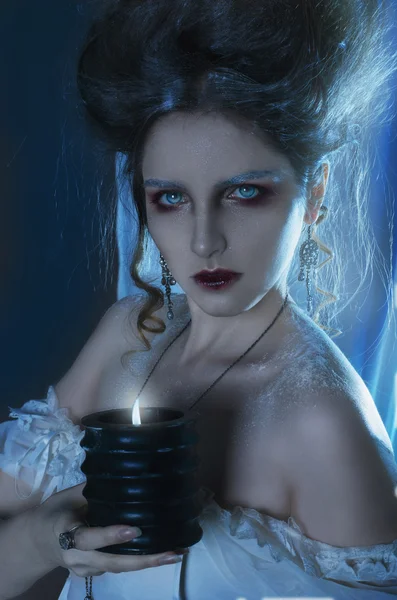 Portrait of a beautiful girl ghost, witch bride in a white dress holding a black burning candle in hands — Stock Photo, Image