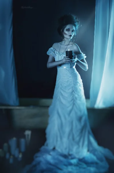 Bela menina fantasma, bruxa noiva em um vestido branco segurando uma vela queimando preto nas mãos — Fotografia de Stock