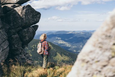 Yaz günü sırt çantasıyla yürüyüş yapan ve sırıkla yürüyüş yapan bir kadın. Ukrayna Karpat Dağlarında Doğa Turizmi.