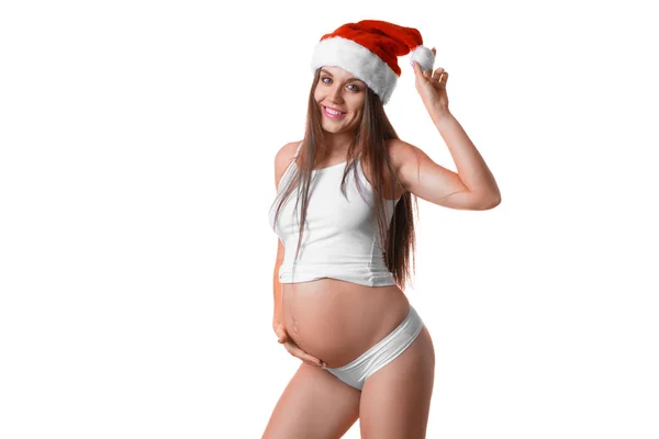 Беременная женщина в нижнем белье и шляпе Санты на белом фоне. Стоковое Фото